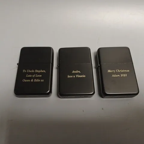 THREE ASSORTED ENGRAVED BLACK LIGHTERS