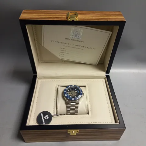 BOXED MENS DESCHAMPS & CO AUTOMATIC WATCH BLUE SKELETON DIAL AND A STAINLESS STEEL STRAP