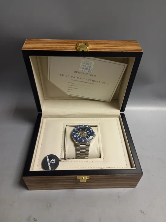 BOXED MENS DESCHAMPS & CO AUTOMATIC WATCH BLUE SKELETON DIAL AND A STAINLESS STEEL STRAP