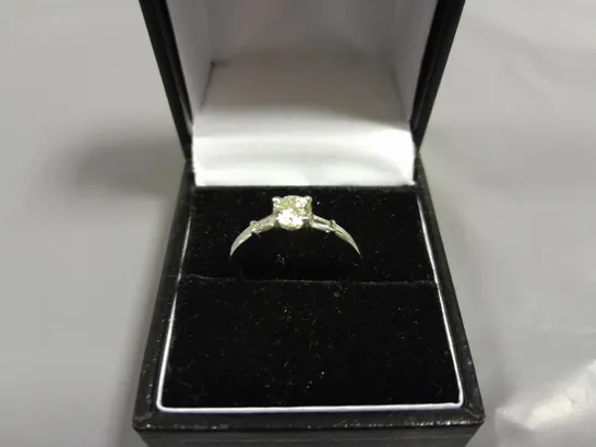 18CT WHITE GOLD RING SET WITH A NATURAL DIAMOND TO THE CENTRE AND A BAGUETTE TO EACH SHOULDER