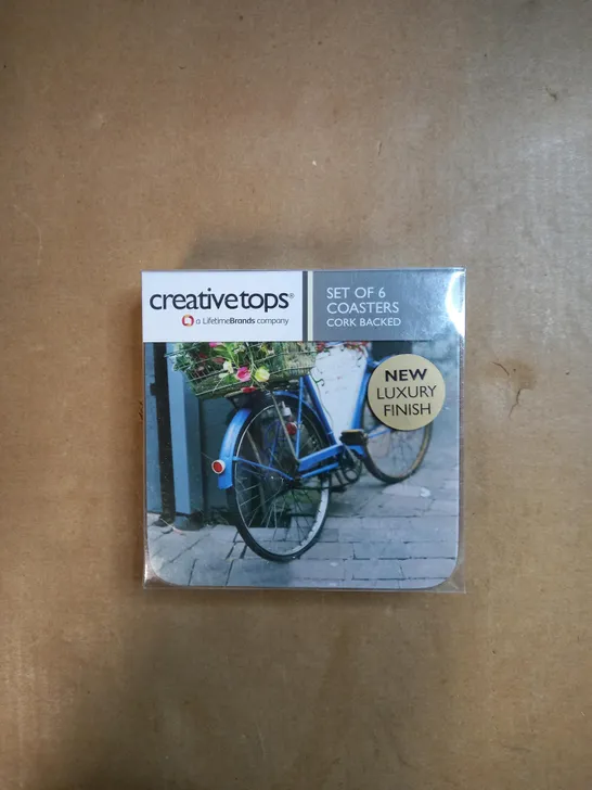 BOX OF APPROXIMATELY 30 PACKS OF CREATIVE TOPS SET OF 6 CORK BACKED COASTERS IN A VINTAGE BICYCLE DESIGN 