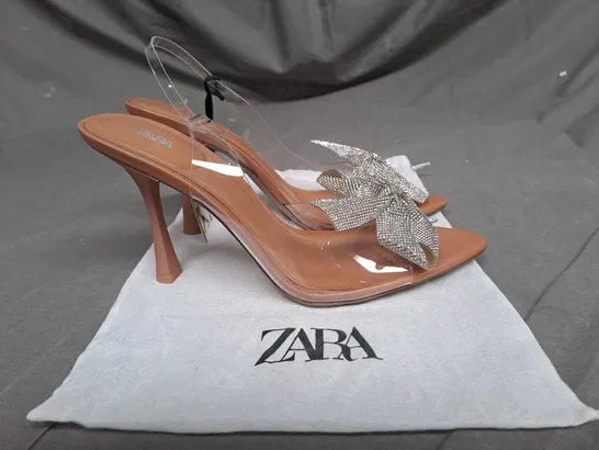 PAIR OF ZARA OPEN TOE HEELS IN CLEAR/TAN WITH SILVER BOW DETAIL SIZE 6