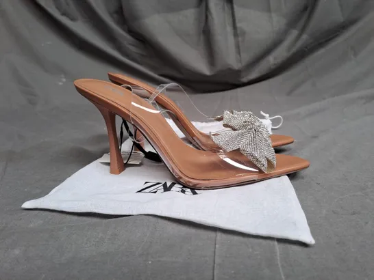 PAIR OF ZARA OPEN TOE HEELS IN CLEAR/TAN WITH SILVER BOW DETAIL SIZE 5