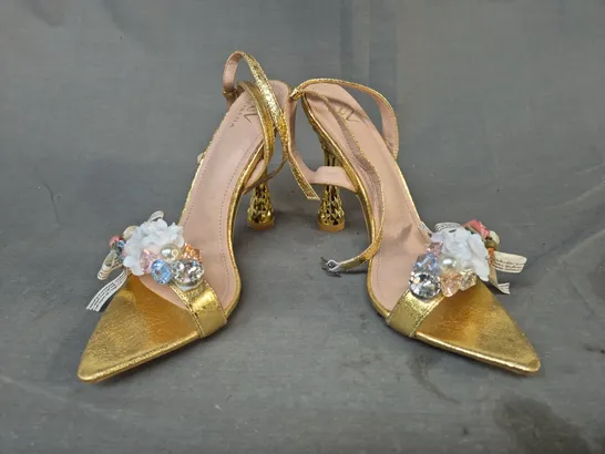 BOXED PAIR OF WEIBENA OPEN TOE HEELED SANDALS IN METALLIC GOLD W. FLORAL & GEM DETAIL EU SIZE 40