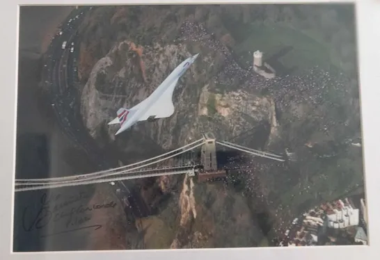 FRAMED AND MOUNTED PHOTOGRAPH OF  THE CONCORDE ON ITS LAST-EVER FLIGHT, OVER THE CLIFTON SUSPENSION BRIDGE IN BRISTOL, WESTERN ENGLAND BY LEWIS WHYLD SIGNED BY CHIEF PILOT CAPTAIN MIKE BANNISTER