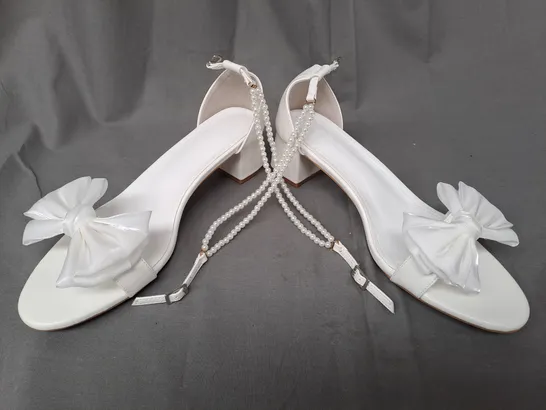 BOXED PAIR OF DESIGNER OPEN TOE BLOCK HEEL BRIDAL STYLE SANDALS IN WHITE W. BOW DETAIL AND PEARL EFFECT STRAP EU SIZE 44