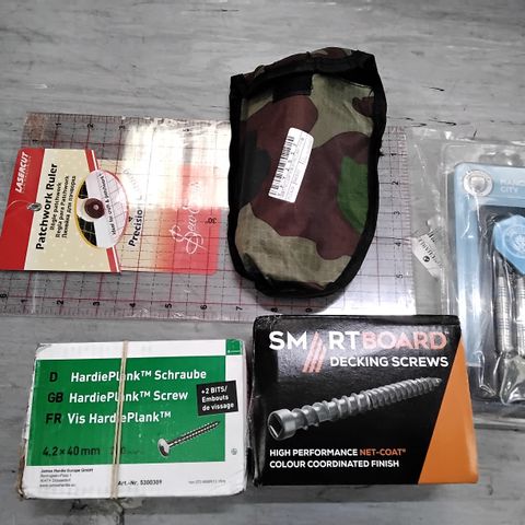 TOTE OF ASSORTED ITEMS INCLUDING HARDIEPLANK SCREWS, PATCHWORK RULER, MINI SHOVEL IN POUCH, DEKING SCREWS, MANCHESTER CITY DART SET