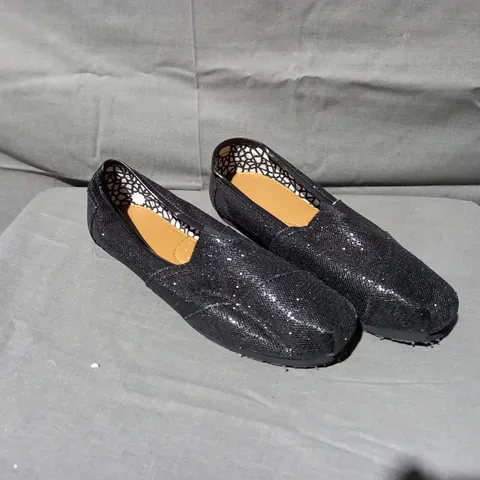 APPROXIMATELY 24 BOXED PAIRS OF FLAT SLIP ON SHOES IN BLACK GLITTER VARIOUS SIZES 6, 7, 8